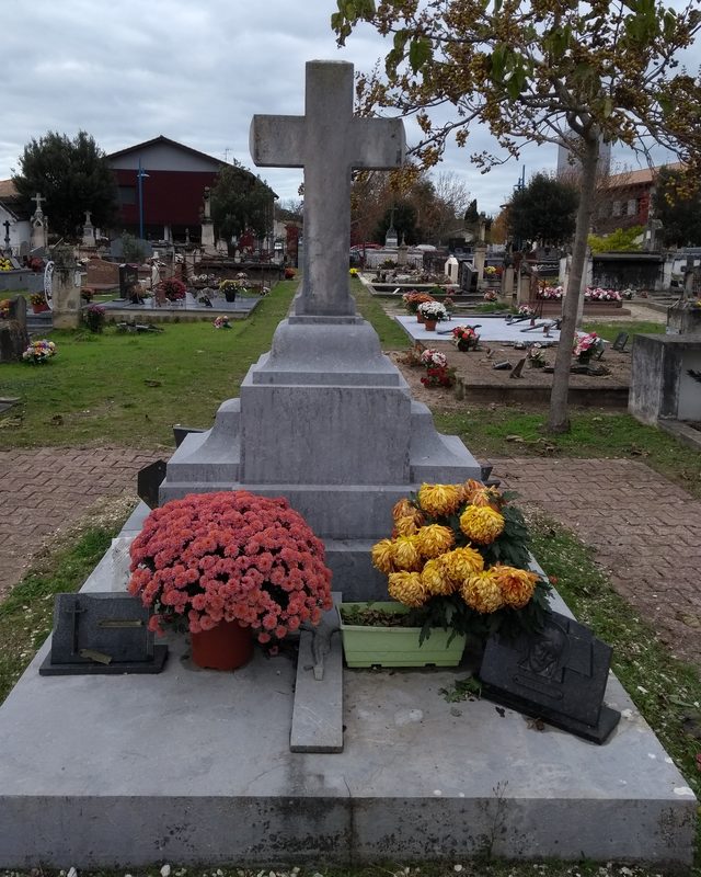 Tombe en granit fleurie de chrysanthèmes rouges et jaunes